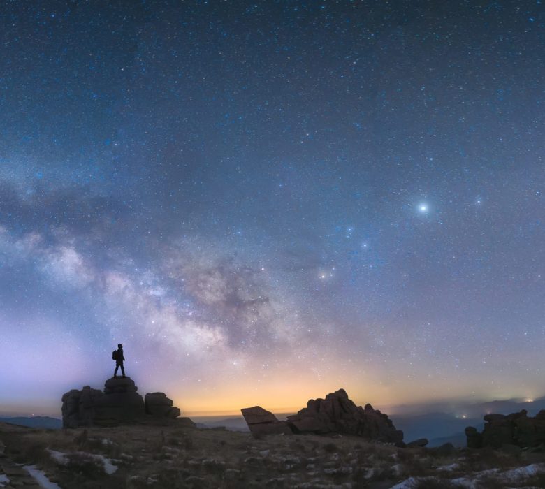 A man standing next to the Milky Way galaxy